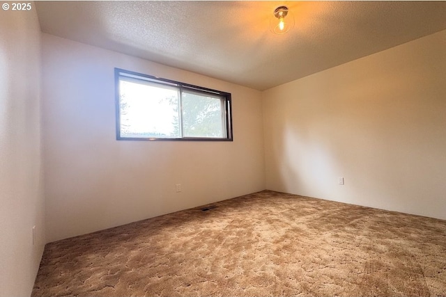 carpeted empty room with a textured ceiling and visible vents