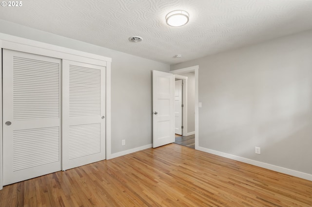 unfurnished bedroom featuring baseboards, a closet, light wood-type flooring, and visible vents
