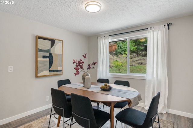 dining space with baseboards, a textured ceiling, and dark wood finished floors