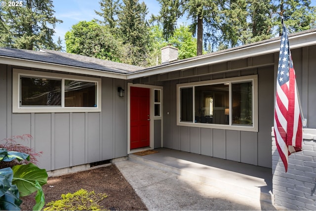 property entrance with a shingled roof, board and batten siding, and a chimney