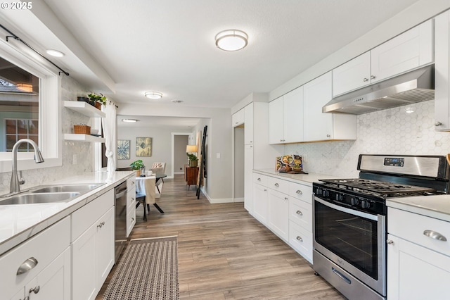 kitchen with open shelves, decorative backsplash, under cabinet range hood, a sink, and appliances with stainless steel finishes