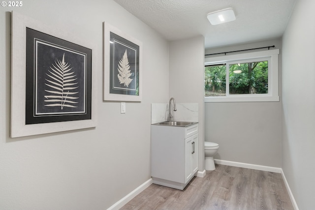 bathroom featuring toilet, baseboards, wood finished floors, and vanity