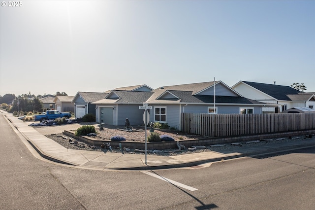 townhome / multi-family property featuring fence private yard, roof with shingles, a residential view, and a garage
