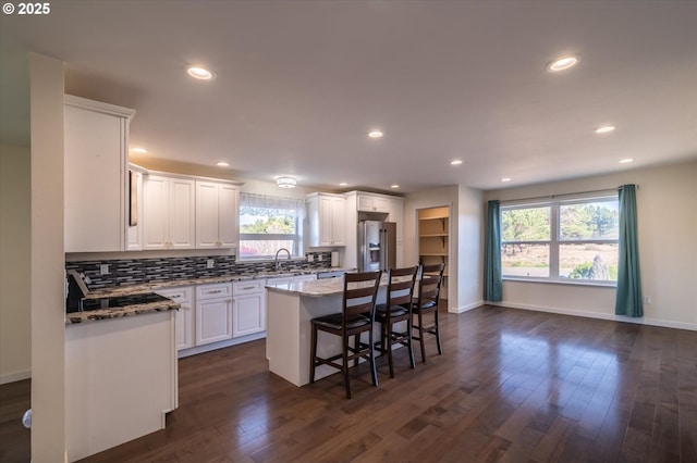 kitchen with dark wood finished floors, stainless steel fridge, white cabinetry, and a sink