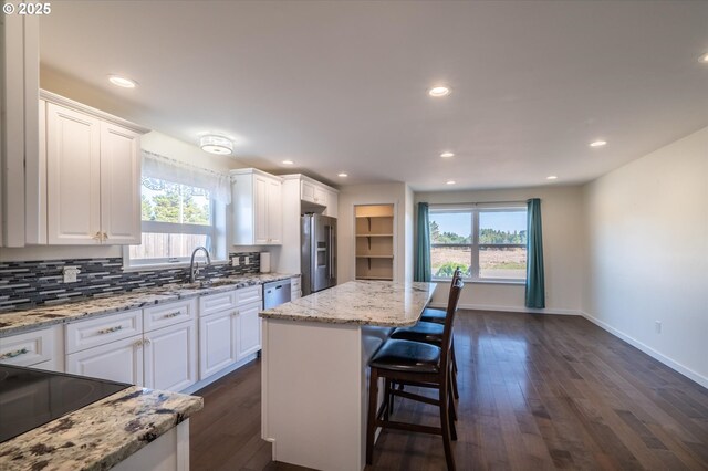 kitchen with a wealth of natural light, a sink, white cabinetry, and stainless steel fridge with ice dispenser