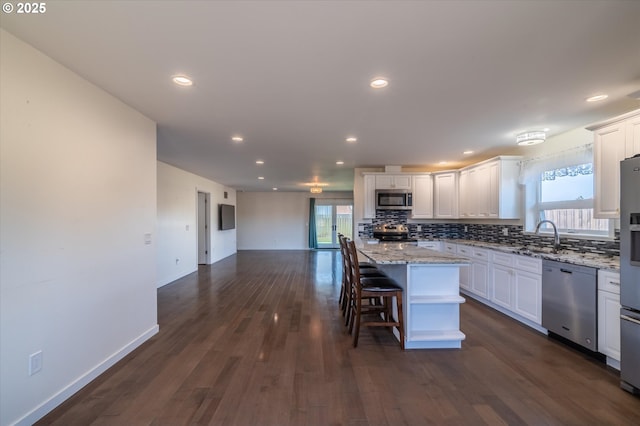 kitchen with a center island, plenty of natural light, white cabinetry, backsplash, and appliances with stainless steel finishes