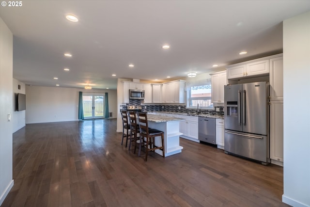 kitchen with white cabinets, decorative backsplash, appliances with stainless steel finishes, and dark wood-type flooring