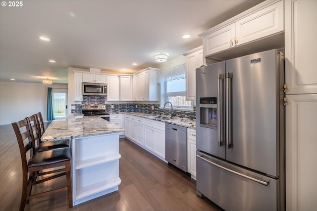 kitchen featuring white cabinets, a sink, tasteful backsplash, light stone countertops, and appliances with stainless steel finishes