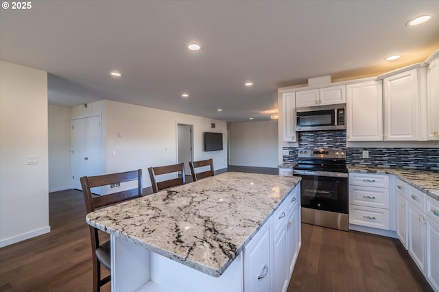 kitchen with white cabinets, backsplash, appliances with stainless steel finishes, and dark wood-style flooring