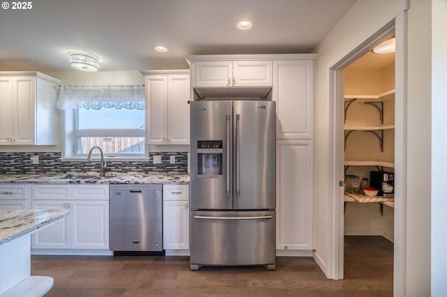 kitchen with white cabinets, light stone countertops, appliances with stainless steel finishes, and a sink