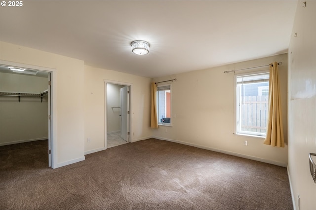 unfurnished bedroom featuring a spacious closet, baseboards, carpet floors, and a closet