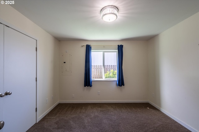 empty room with carpet floors, electric panel, and baseboards