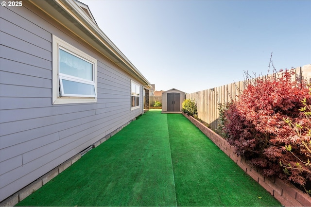 view of yard with a storage shed, an outbuilding, and a fenced backyard