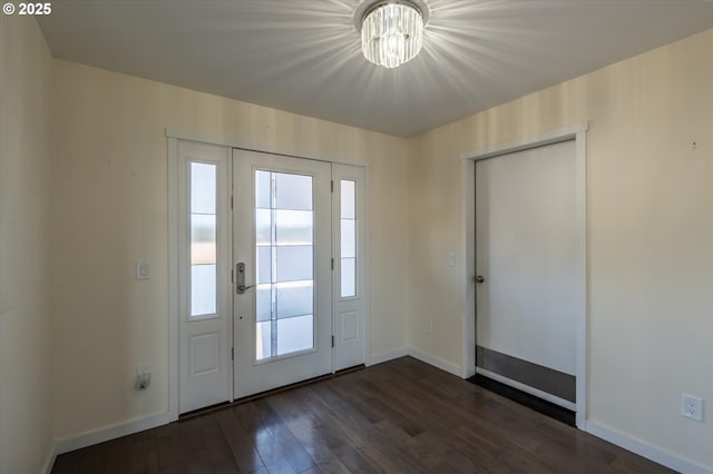 doorway featuring baseboards, a notable chandelier, and dark wood-style flooring