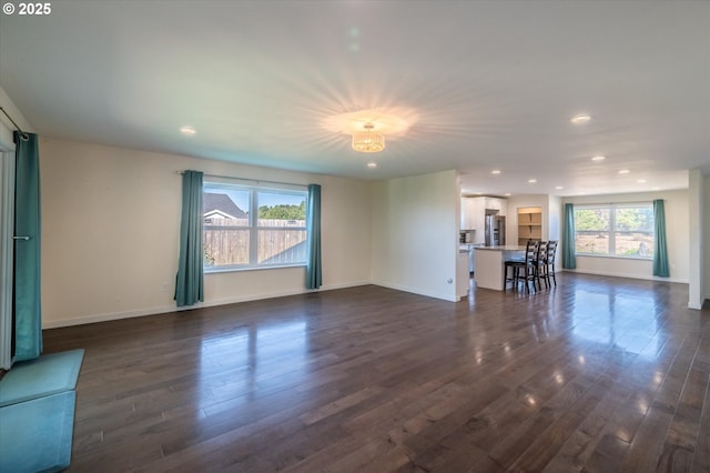 unfurnished living room with baseboards, dark wood-type flooring, and recessed lighting