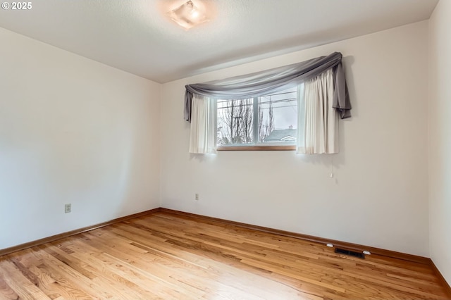 unfurnished room with baseboards, visible vents, and light wood-style floors