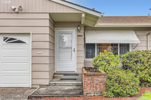 property entrance featuring an attached garage and roof with shingles