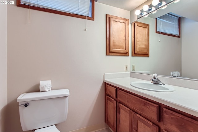 bathroom featuring baseboards, vanity, and toilet