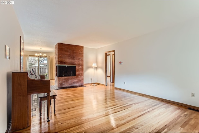 living area with light wood finished floors, baseboards, visible vents, an inviting chandelier, and a brick fireplace