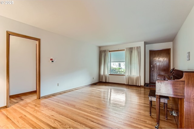 unfurnished living room with radiator, baseboards, and light wood finished floors