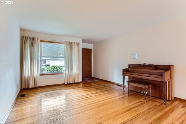 unfurnished room with light wood finished floors, visible vents, and baseboards