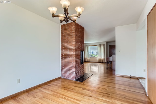 unfurnished living room featuring light wood-type flooring, baseboards, and an inviting chandelier