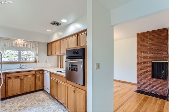 kitchen with light wood-style flooring, white appliances, a sink, visible vents, and light countertops