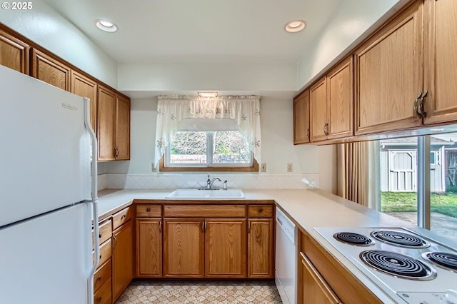 kitchen featuring white appliances, brown cabinets, and a sink