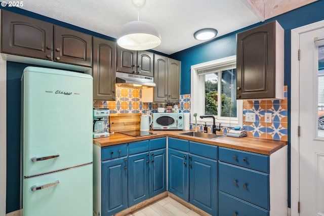 kitchen with fridge, tasteful backsplash, wooden counters, black electric cooktop, and sink