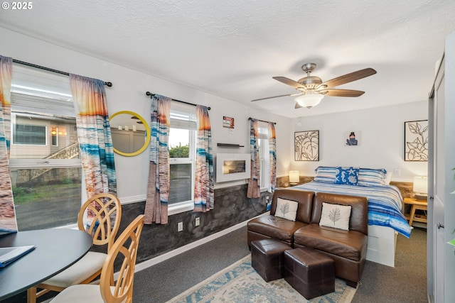 carpeted bedroom with ceiling fan, a textured ceiling, and a fireplace