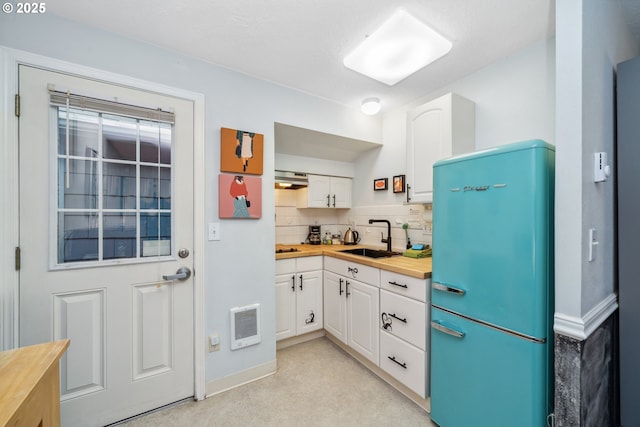 kitchen featuring backsplash, white cabinetry, refrigerator, and butcher block counters