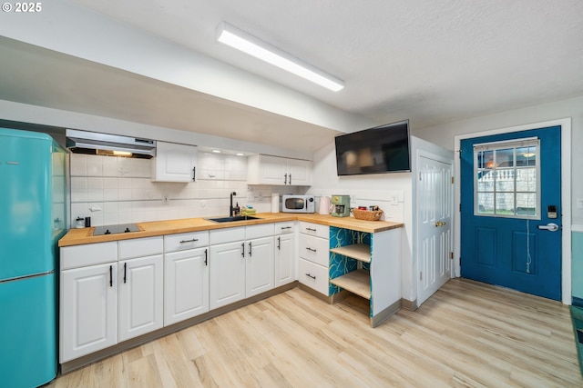 kitchen with sink, wood counters, and white cabinetry