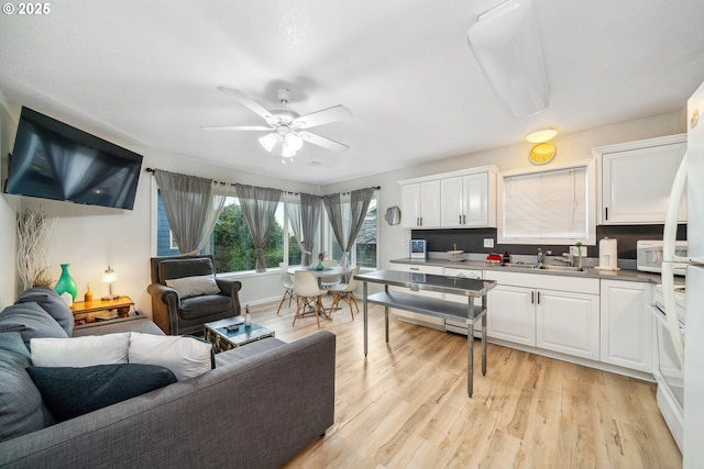 kitchen featuring sink, ceiling fan, white cabinetry, and light hardwood / wood-style flooring