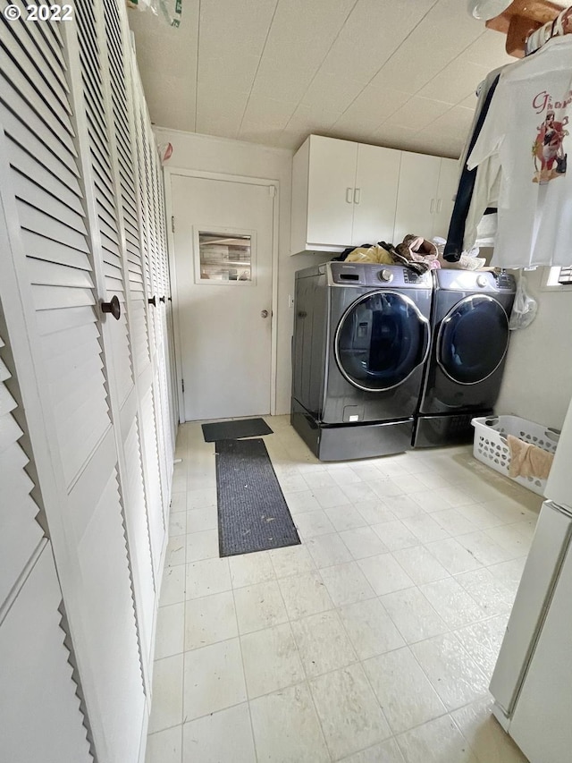 laundry room featuring separate washer and dryer, cabinets, and light tile floors