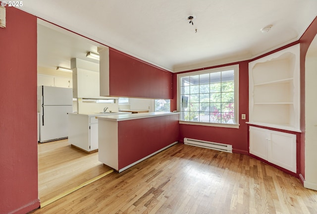 412 W 17th Ave, Eugene, OR 97401 - kitchen with freestanding refrigerator, a baseboard heating unit, light wood-style floors, a peninsula, and white cabinetry