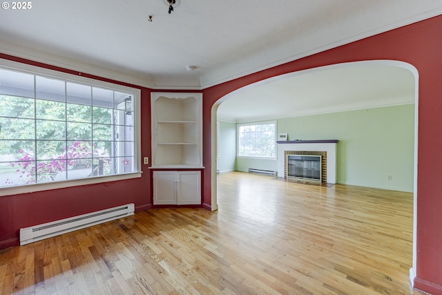 412 W 17th Ave, Eugene, OR 97401 - unfurnished living room featuring baseboard heating, arched walkways, wood finished floors, and a brick fireplace