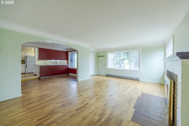 412 W 17th Ave, Eugene, OR 97401 - unfurnished living room featuring baseboard heating, arched walkways, crown molding, wood finished floors, and healthy amount of natural light
