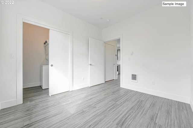 spare room featuring stacked washing maching and dryer and light wood-type flooring