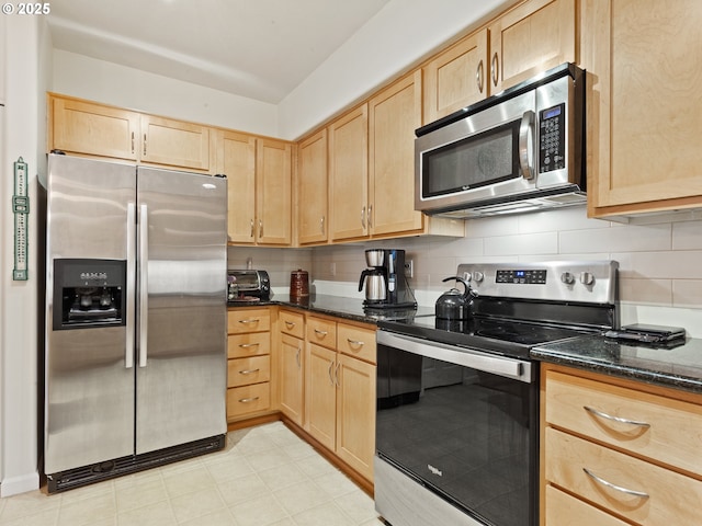 kitchen featuring backsplash, dark stone counters, light brown cabinets, and stainless steel appliances