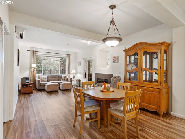 dining room with a tiled fireplace and wood finished floors