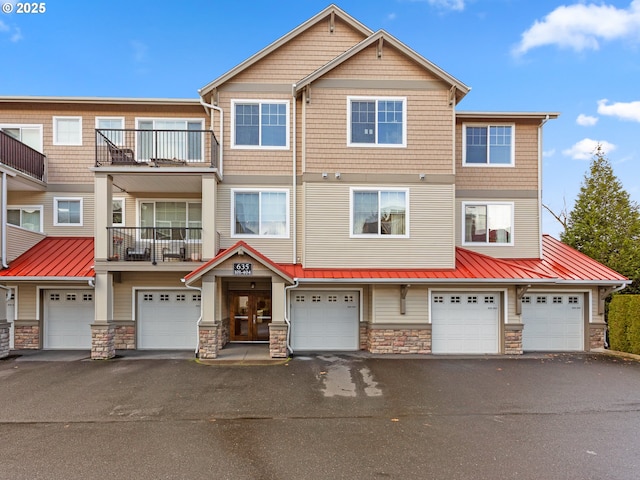 multi unit property featuring driveway, a garage, and stone siding