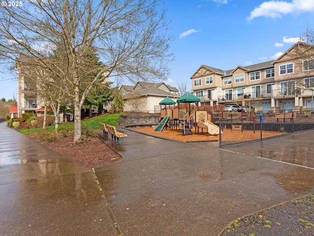 community play area featuring fence and a residential view