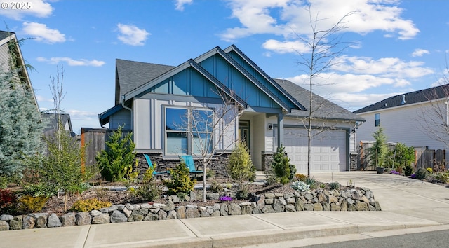 view of front facade with fence, driveway, an attached garage, stone siding, and board and batten siding