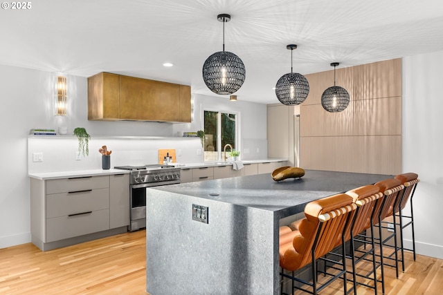 kitchen with pendant lighting, light hardwood / wood-style flooring, gas stove, and a kitchen breakfast bar