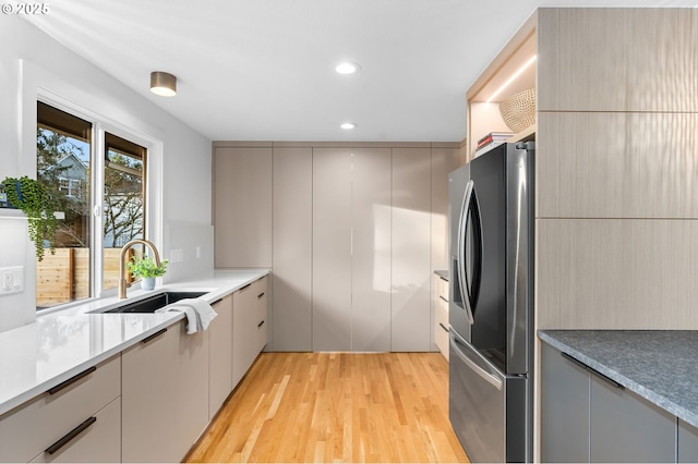 kitchen featuring stainless steel refrigerator with ice dispenser, sink, gray cabinetry, and light hardwood / wood-style flooring