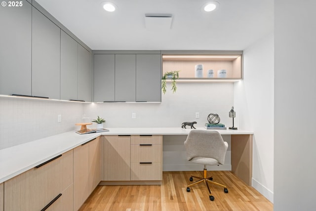 office space with built in desk and light wood-type flooring