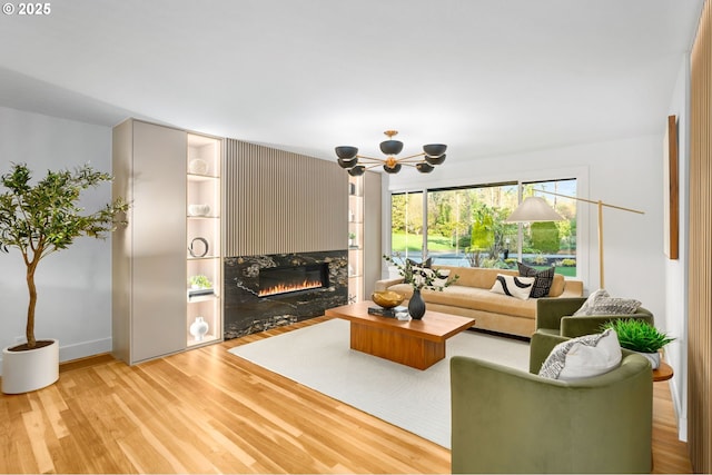 living room featuring an inviting chandelier, built in features, and light hardwood / wood-style flooring