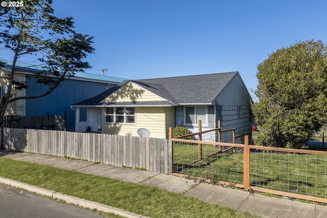 view of front of property featuring a fenced front yard and a shingled roof