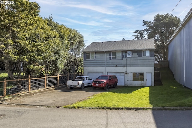 view of front of house with driveway, a front lawn, a garage, and fence