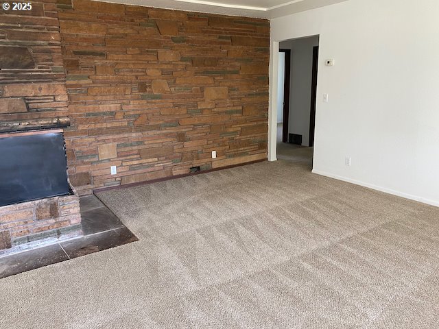 carpeted empty room featuring a fireplace and baseboards